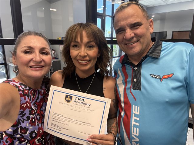 A TRA Academy student holding their certificate of completion with instructors Nora Acosta and John Endres